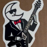 Tuscan Travellers commemorative logo featuring a stylized figure in formal attire playing a guitar labeled Arkona, representing their visit to Arkona Lodge No. 307