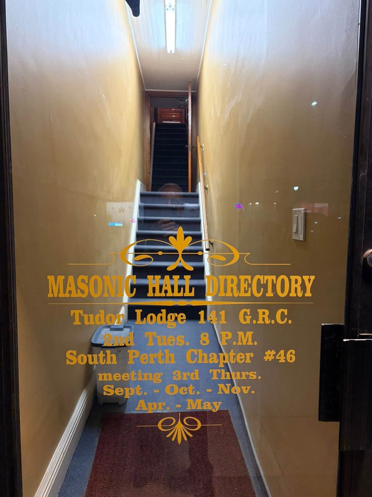 Glass entrance to Tudor Lodge No. 141 Masonic Hall in Mitchell, Ontario, displaying the lodge directory and meeting information.