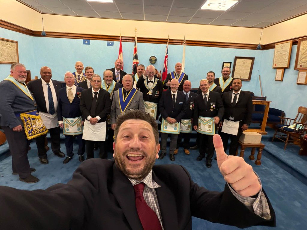 Freemasons gathered for a group photograph inside Tudor Lodge No. 141 in Mitchell, Ontario, wearing traditional Masonic aprons and regalia.
